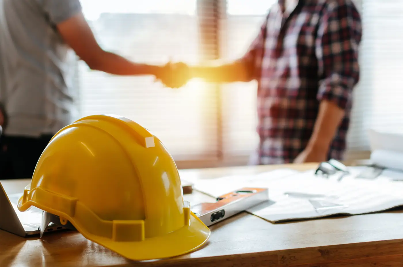 Construction project scene with handshake, hard hat, blueprints symbolizing cooperation